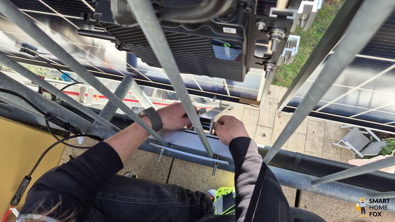 Die Module des Solakon onLite 900w Balkonkraftwerks werden am Balkongeländer mit ausfahrbaren Teleskopstangen. angebracht und befestigt.